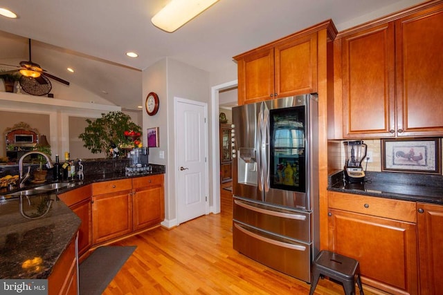 kitchen with brown cabinetry, light wood finished floors, ceiling fan, a sink, and stainless steel fridge