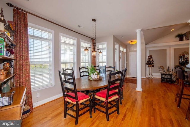 dining area with baseboards, light wood-style flooring, and ornate columns