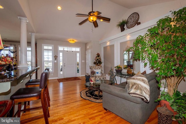 living area featuring ceiling fan, lofted ceiling, light wood-style flooring, and ornate columns