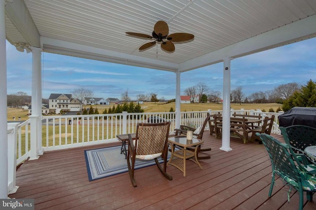 wooden terrace with a yard, outdoor dining area, and a ceiling fan