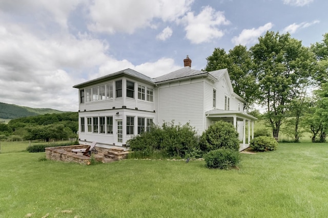 back of property with a sunroom and a lawn