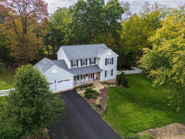 view of front facade with driveway, a porch, fence, a front yard, and a garage