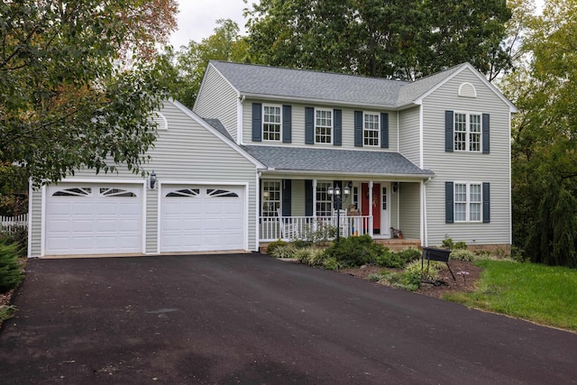 traditional-style house with driveway, roof with shingles, covered porch, and an attached garage