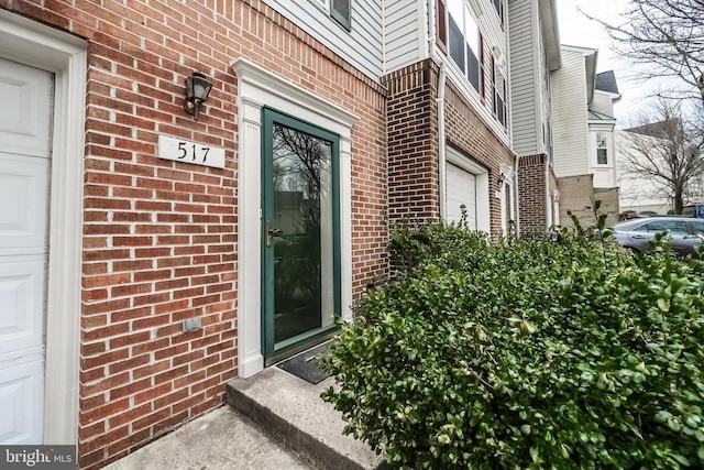 property entrance featuring brick siding and an attached garage