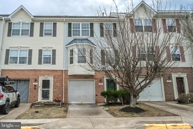 view of property featuring a garage, brick siding, and driveway