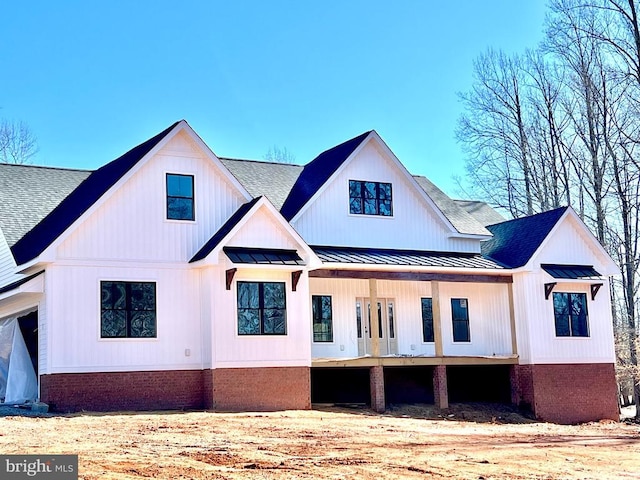 back of property with a standing seam roof, metal roof, brick siding, and roof with shingles