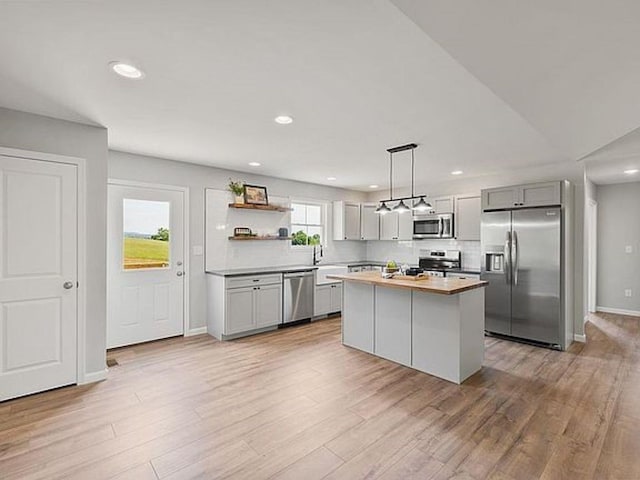 kitchen featuring a kitchen island, gray cabinetry, hanging light fixtures, stainless steel appliances, and light hardwood / wood-style flooring