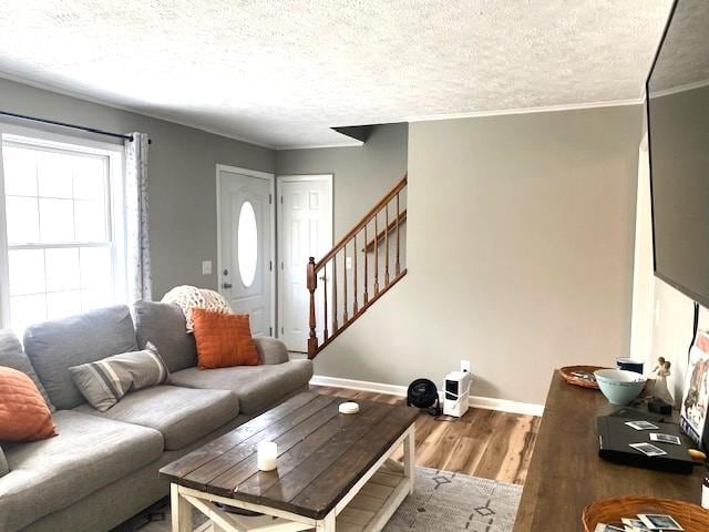 living room featuring stairs, crown molding, baseboards, and wood finished floors