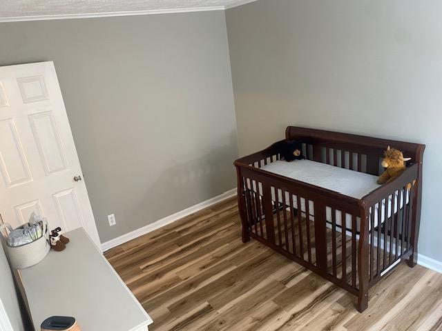 bedroom with baseboards, wood finished floors, and ornamental molding