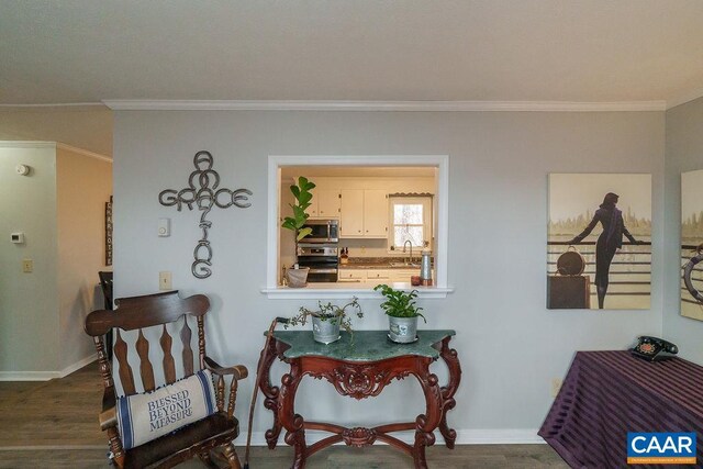 sitting room with dark wood-style floors, crown molding, and baseboards