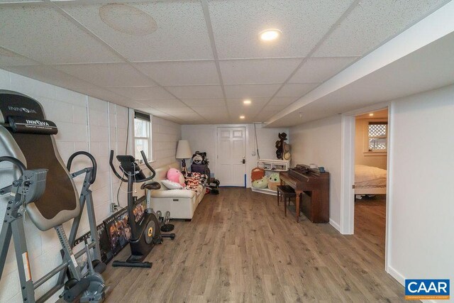 exercise area featuring baseboards, a drop ceiling, wood finished floors, and recessed lighting