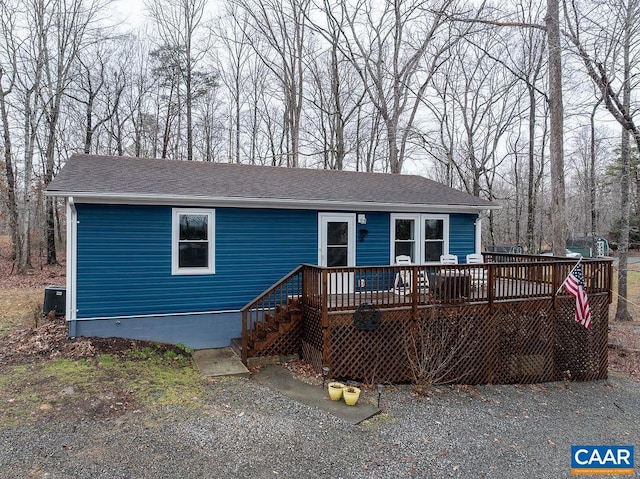 view of front facade featuring central air condition unit, a deck, and roof with shingles