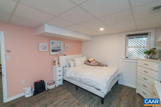 bedroom with dark wood-style floors, a paneled ceiling, visible vents, and baseboards