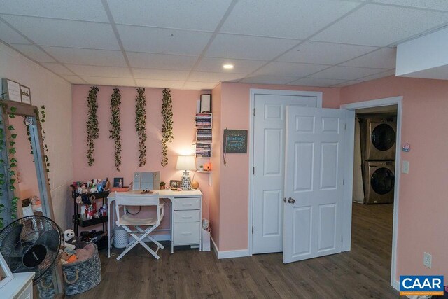 unfurnished office with dark wood-style floors, stacked washer / dryer, a paneled ceiling, and baseboards