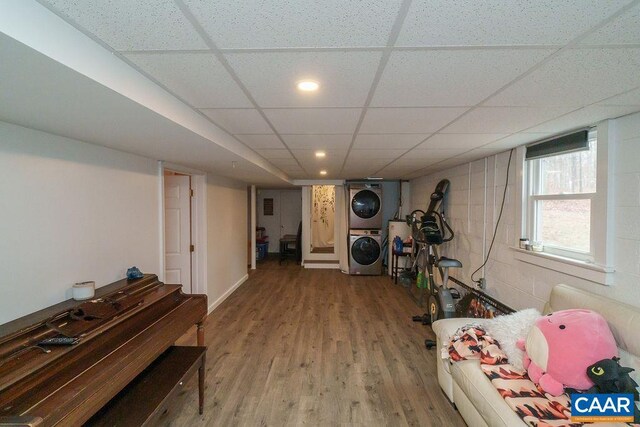 exercise area with concrete block wall, recessed lighting, stacked washing maching and dryer, wood finished floors, and a drop ceiling