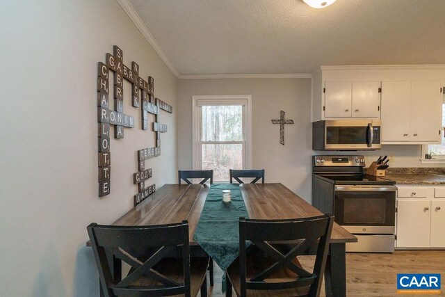 dining area with ornamental molding and light wood finished floors