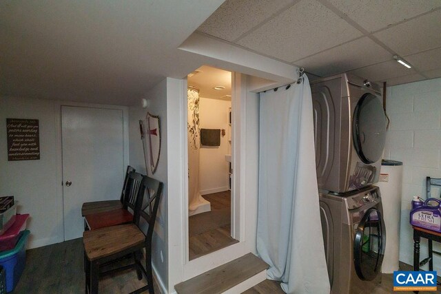 full bath featuring stacked washer / drying machine, a drop ceiling, a shower with shower curtain, and wood finished floors