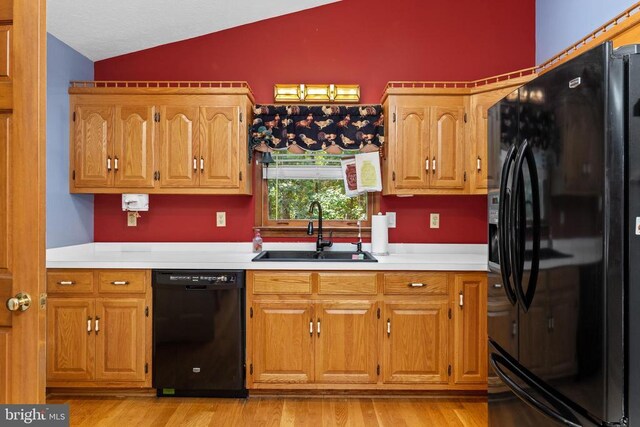 kitchen with vaulted ceiling, sink, light hardwood / wood-style floors, and black appliances