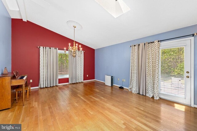 unfurnished dining area featuring an inviting chandelier, wood-type flooring, vaulted ceiling with skylight, and plenty of natural light