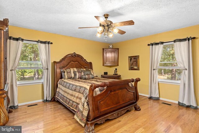 bedroom featuring ceiling fan, a textured ceiling, and light wood-type flooring