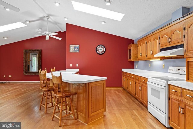 kitchen featuring light hardwood / wood-style flooring, white range with electric cooktop, a kitchen breakfast bar, a center island, and vaulted ceiling