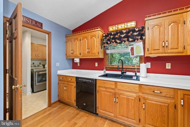 kitchen featuring sink, light hardwood / wood-style flooring, black dishwasher, washer and dryer, and vaulted ceiling