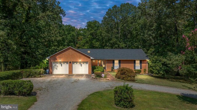 ranch-style home featuring a garage and a yard