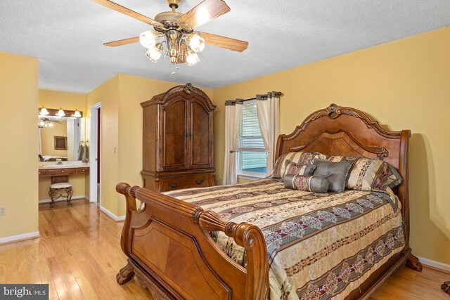 bedroom with ceiling fan, light hardwood / wood-style flooring, a textured ceiling, and ensuite bathroom