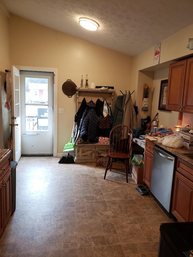 kitchen featuring dark stone countertops, a textured ceiling, vaulted ceiling, and dishwasher