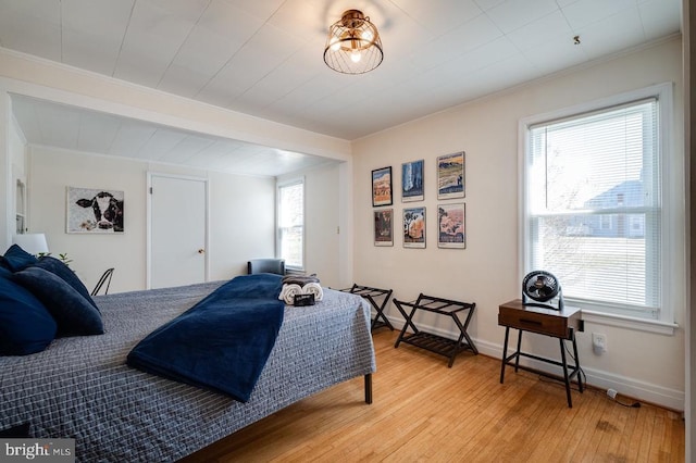 bedroom featuring baseboards, light wood-style flooring, and ornamental molding