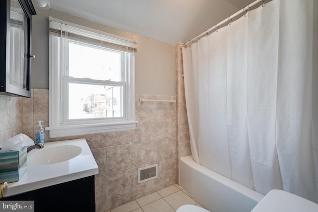 full bathroom with tile patterned flooring, visible vents, toilet, vanity, and tile walls