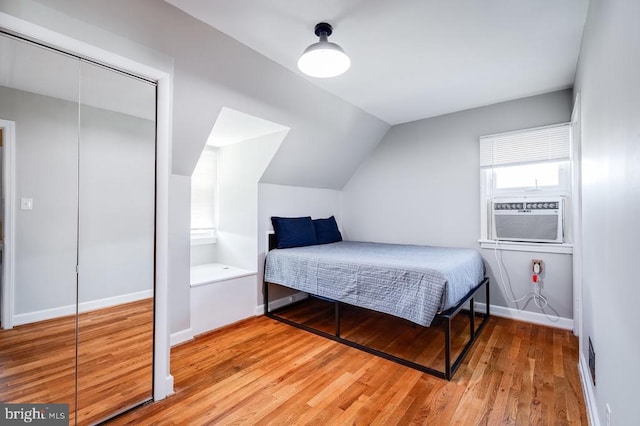 bedroom featuring light wood-type flooring, cooling unit, lofted ceiling, and baseboards