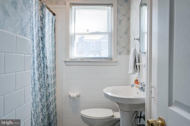 full bath featuring a shower with shower curtain, toilet, and tile walls