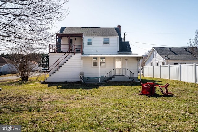 back of property featuring stairway, a chimney, a yard, and fence