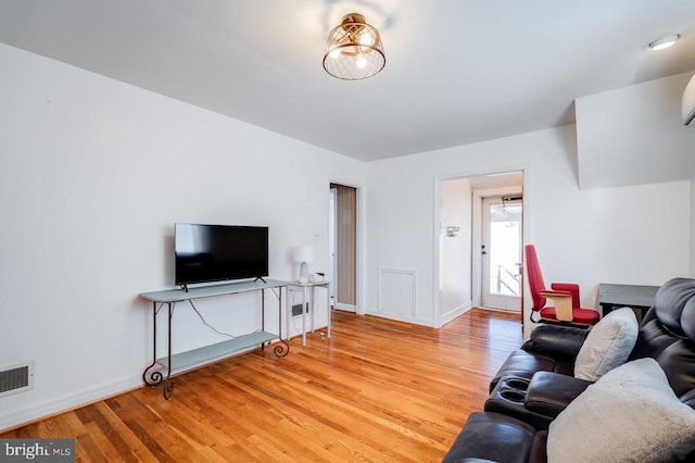 living room with light wood-type flooring, baseboards, and visible vents