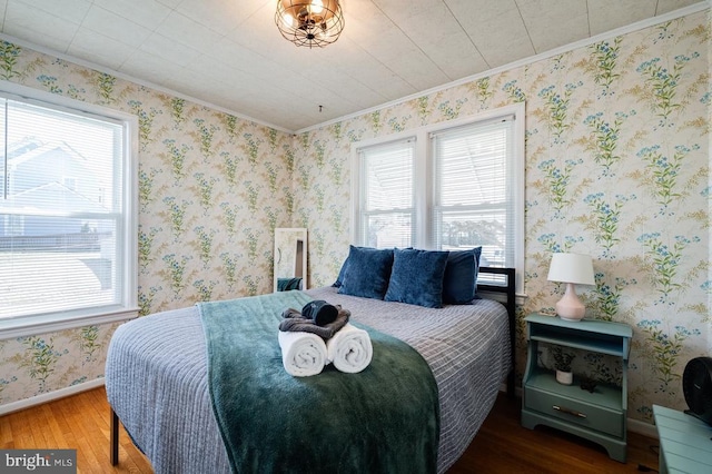 bedroom featuring wallpapered walls, crown molding, wood finished floors, and baseboards