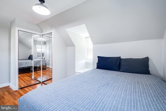 bedroom with a closet, lofted ceiling, baseboards, and wood finished floors