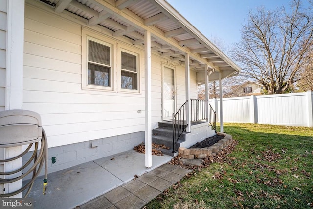 doorway to property with fence, a lawn, and crawl space