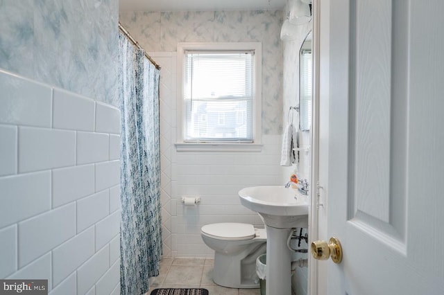 full bathroom with a wainscoted wall, curtained shower, tile walls, toilet, and tile patterned floors