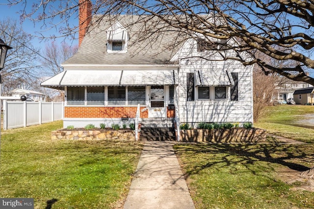 view of front facade featuring a front yard, fence, brick siding, and a chimney