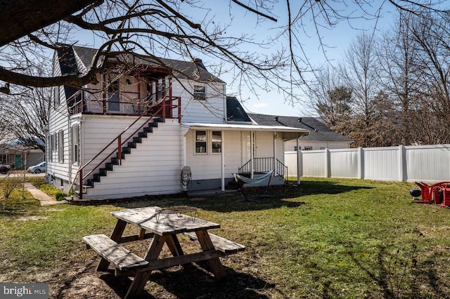 back of house with a yard, a shingled roof, and fence