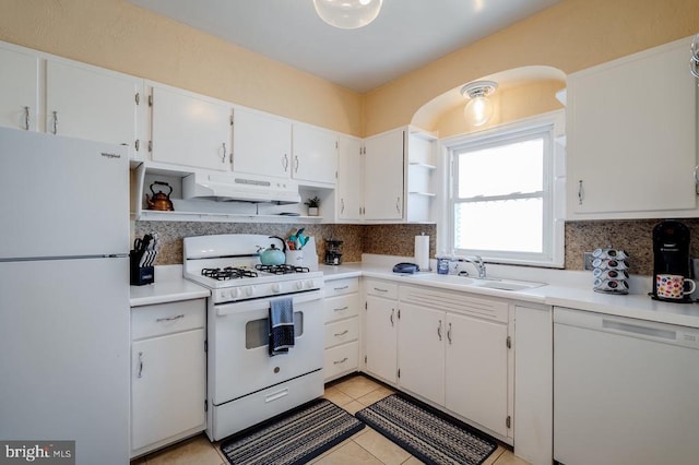 kitchen with under cabinet range hood, open shelves, a sink, tasteful backsplash, and white appliances