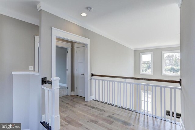 corridor with ornamental molding and light hardwood / wood-style floors