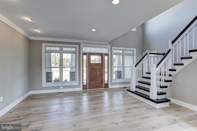 entryway with ornamental molding, plenty of natural light, and light hardwood / wood-style flooring