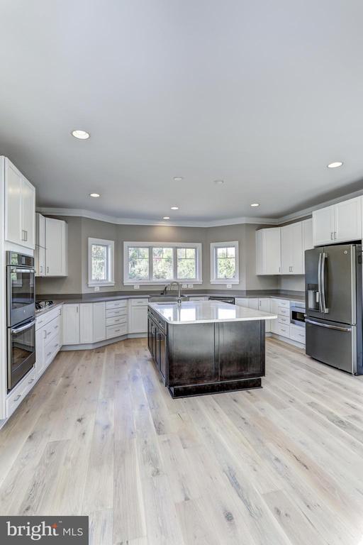 kitchen featuring white cabinetry, light wood-type flooring, stainless steel appliances, and a center island with sink