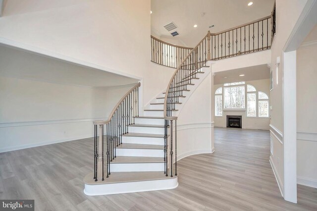 stairs featuring a towering ceiling and wood-type flooring