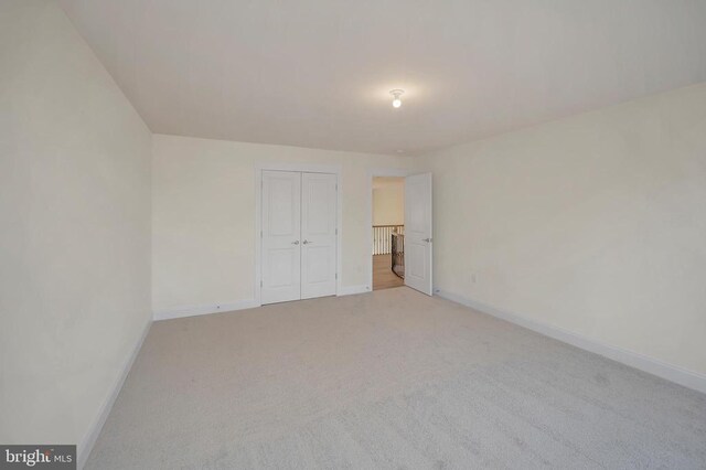 unfurnished bedroom with light colored carpet and a closet