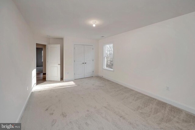 unfurnished bedroom featuring a closet and light carpet