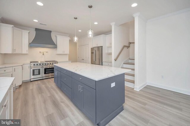 kitchen featuring a kitchen island, white cabinets, premium appliances, light stone counters, and custom range hood