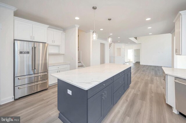 kitchen featuring white cabinetry, hanging light fixtures, appliances with stainless steel finishes, a kitchen island, and light stone countertops